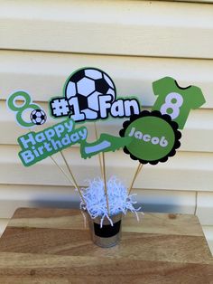 a cup filled with cake toppers sitting on top of a wooden table next to a wall