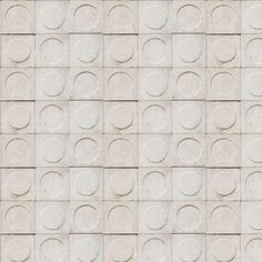 a wall made up of white tiles with circles on the top and one circle in the middle