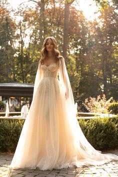 a woman in a wedding dress standing on a stone walkway with trees in the background