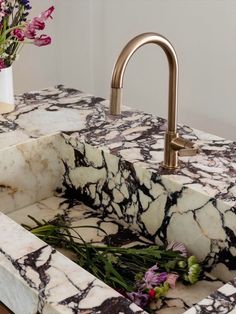 a marble sink with gold faucet and flowers in the corner on instagram