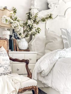 a bedroom with white furniture and flowers in vases