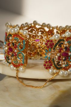 Adorn your wrist with the "Shama - Bangle," a luscious ensemble meticulously beautified by experts to infuse vibrant color into your festive attire. This exquisite bangle is embellished with the timeless beauty of multi-color stones, enhanced by a delicate addition of pearl moti, making it the perfect accessory to showcase elegance with contemporary style.The "Shama" bangle is designed with convenience in mind, featuring an openable design in the middle for easy wearing. It is a one-size-fits-mo Festive Attire, Color Stones, Pakistani Jewelry, Necklace Sets, Jhumka Earrings, Timeless Beauty, Bridal Jewelry, Jewelry Shop, Timeless Elegance