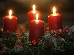 three red candles sitting on top of a christmas wreath