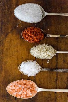 three spoons filled with different types of food on top of a wooden table next to each other