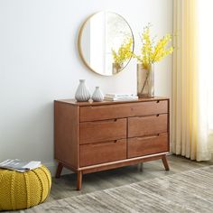 a wooden dresser with two vases on top and a mirror in the corner next to it