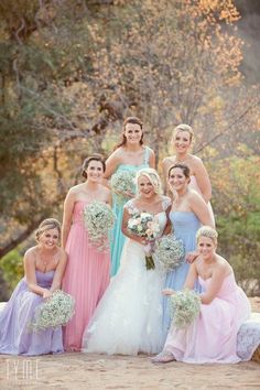 a group of women standing next to each other wearing dresses and holding bouquets in their hands