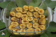 a glass dish filled with sliced bananas and other fruits on top of leafy leaves