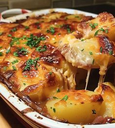 a casserole dish with potatoes and ham being lifted from the casserole