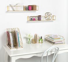 a white desk topped with lots of shelves filled with books and crafting supplies next to a chair