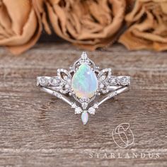 an opal and diamond ring sits on a wooden table