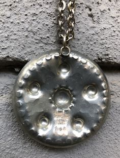 "Vintage pewter pendant necklace by Jorgen Jensen, Denmark. The hand made pendant is round with a nice pattern and raised edges. The diameter measures 2\" / 5cm and the chain measures 36\" / 91cm. Marked: \"PEWTER Jorgen Jensen HANDMADE DENMARK 158\" It's from the 1960's and shows minor wear, such as small scratches, for it's age. Please see all pictures." Artisan Stamped Round Pendant Necklace, Silver Stamped Amulet Necklace, Vintage Sterling Silver Medallion Necklace, Vintage Sterling Silver Round Pendant Medallion Necklace, Vintage Sterling Silver Medallion Necklace With Round Pendant, Silver Stamped Round Pendant Necklace, Silver Round Stamped Necklaces, Silver Necklace With Stamped Round Pendant, Antique Silver Stamped Round Necklaces