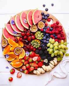 a wooden platter filled with fruits and berries