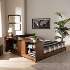 a bed sitting in a bedroom next to a wooden table with a potted plant on it