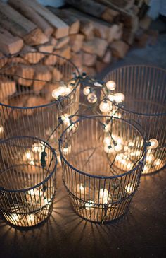 four wire baskets filled with lit candles on top of a table