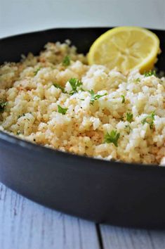 a pan filled with rice and lemon wedges