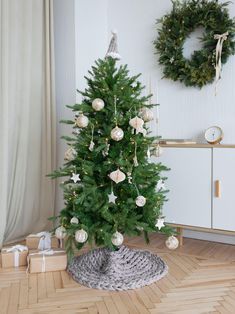 a small christmas tree in a room with presents on the floor and a wreath hanging from the wall