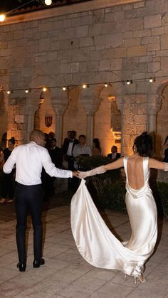 a bride and groom dancing at their wedding reception in front of an old stone building