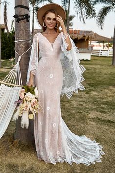 a woman standing next to a tree wearing a dress and hat