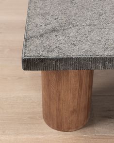 a close up of a table on a wooden floor with a wood base and grey granite top