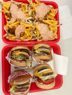 two red trays filled with sandwiches and fries