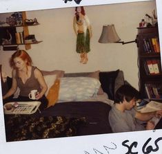 two people sitting on a bed with books and magazines in front of them, one reading a book