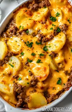 a casserole dish with potatoes, meat and cheese in it on a marble surface