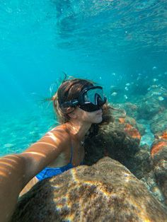 a woman wearing goggles and snorkels is swimming in the blue water