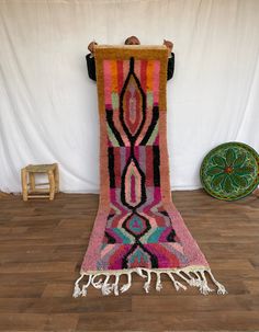 a colorful rug with tassels is on the floor in front of a white backdrop