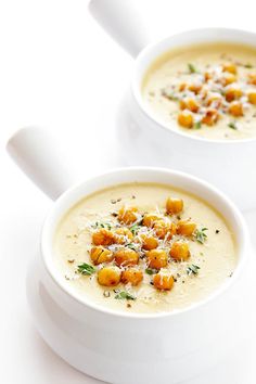 two white bowls filled with soup on top of a table