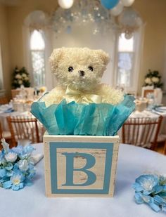 PLEASE READ: THIS WOOD IS DISTRESSED-it is supposed to have a rustic, aged appearance.  This adorable baby block makes a great centerpiece for a baby boy shower, nursery room decoration, and gift for a mom of a sweet baby boy! A distressed wooden box spells the word "B A B Y" in light blue vinyl (one letter on each side of the box) to resemble a block and is topped with an adorable white teddy bear and light blue tissue paper. Measurements are approximately:  12"L x 8"W by 12"H (tip-to-tip). *I' Teddy Bear Table Centerpieces Boys, Teddy Bear And Flowers Centerpieces, Baby Shower Bear Centerpieces, Teddy Bear Floral Centerpieces, Flower Centerpieces For Baby Shower Boy, Baby Shower Teddy Bear Centerpieces, Teddy Bear Basket Table Centerpieces, Snoopy Baby Shower Theme, Teddy Bear Baby Shower Centerpiece