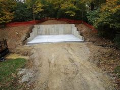 a concrete slab is being built in the middle of a dirt road surrounded by trees