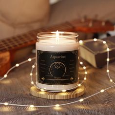 a candle sitting on top of a table next to a string of lights and a guitar