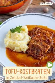 a white plate topped with mashed potatoes and gravy next to a pot of stew