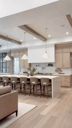 a large open concept kitchen and living room with wood flooring, white countertops and beige furniture