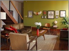 a living room filled with lots of furniture next to a stair case covered in pictures