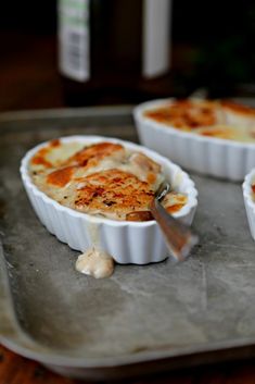 three white dishes filled with food sitting on top of a pan