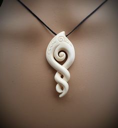 a white necklace with a spiral design on it's end and a black cord