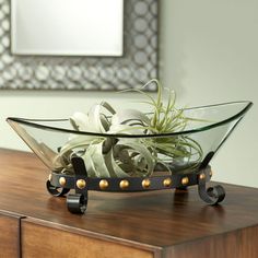 an air plant is in a glass bowl on a wooden table next to a mirror