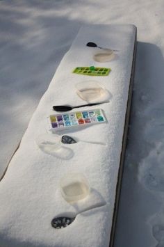 several spoons are lined up on a snow covered bench in the middle of winter