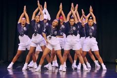 a group of young women standing on top of a stage holding hands in the air