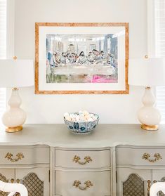 a bowl of eggs sits on top of a dresser in front of a framed painting