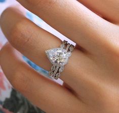 a woman's hand with a diamond ring on top of her finger and an engagement band