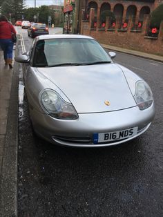 a silver sports car is parked on the side of the road next to a curb