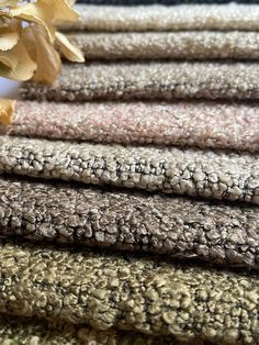 several different colored rugs stacked on top of each other with flowers in the background