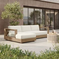 a white couch sitting on top of a patio next to a table and tree in front of a building