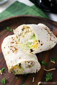 two burritos sitting on top of a wooden plate