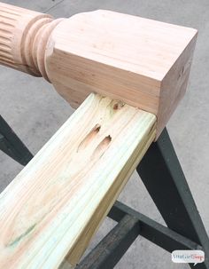 a piece of wood that is sitting on a metal stand with a wooden pole attached to it