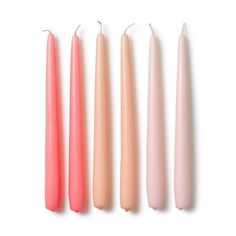 three candles are lined up next to each other on a white surface, one is pink and the other two are peach