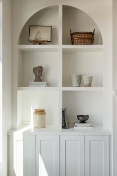 a white shelf with some books and bowls on it