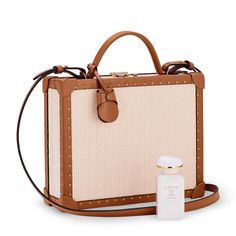 This limited-edition AERIN x Tanner Krolle collaboration features a classic briefcase presented in raffia trimmed in studded leather. It includes a detachable and adjustable leather shoulder strap, light gold key lock, and a foil embossed logo. A perfect bag to carry beauty essentials, this exclusive set also features AERIN’s new modern rose fragrance, Rose de Grasse Joyful Bloom, inspired by Aerin Lauder’s favorite flower. The scent is beautifully presented in a blush pink box, ready to gift. Aerin Lauder, Gold Key, Rose Fragrance, Favorite Flower, Pink Box, Key Lock, Logo A, Studded Leather, Box Bag